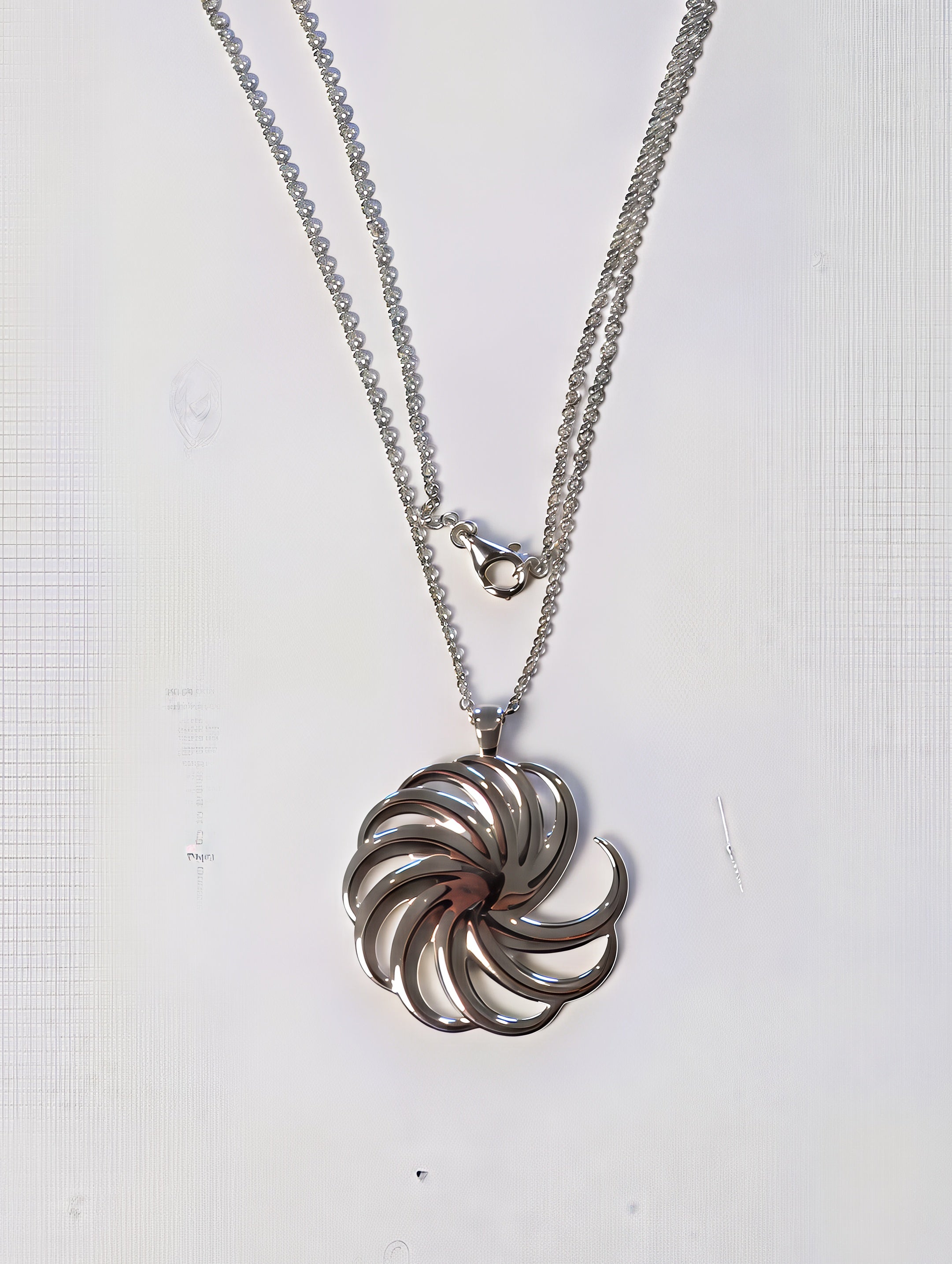 silver spiral pendant on white background with chain and claw clasp