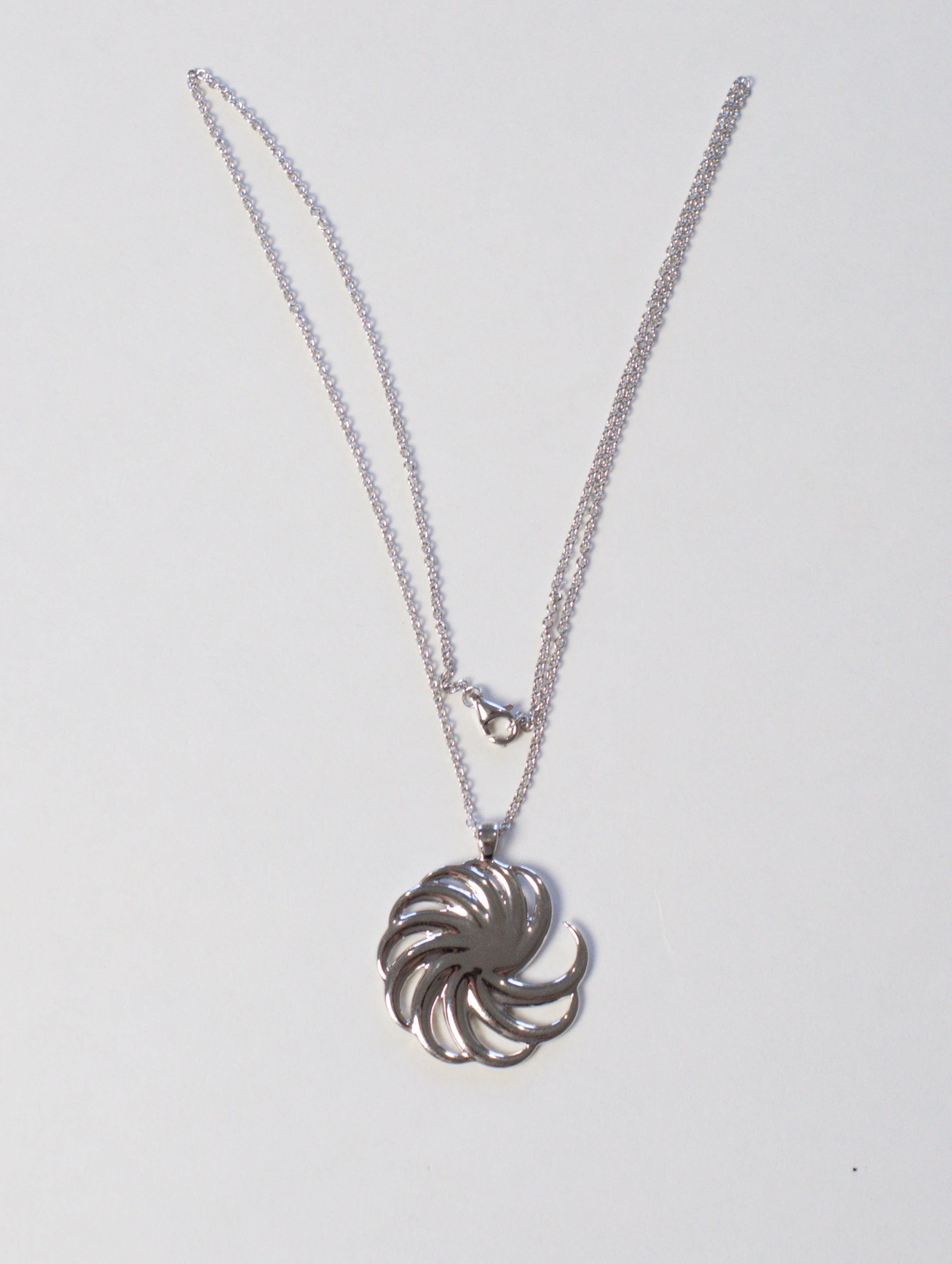 silver spiral pendant with chain showing clasp on white background