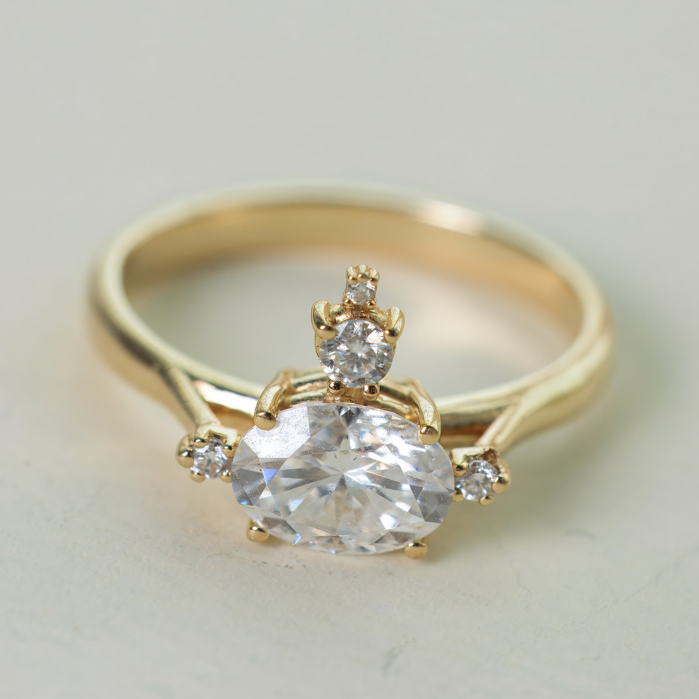 Gold ring with a large diamond and smaller diamonds on a light background