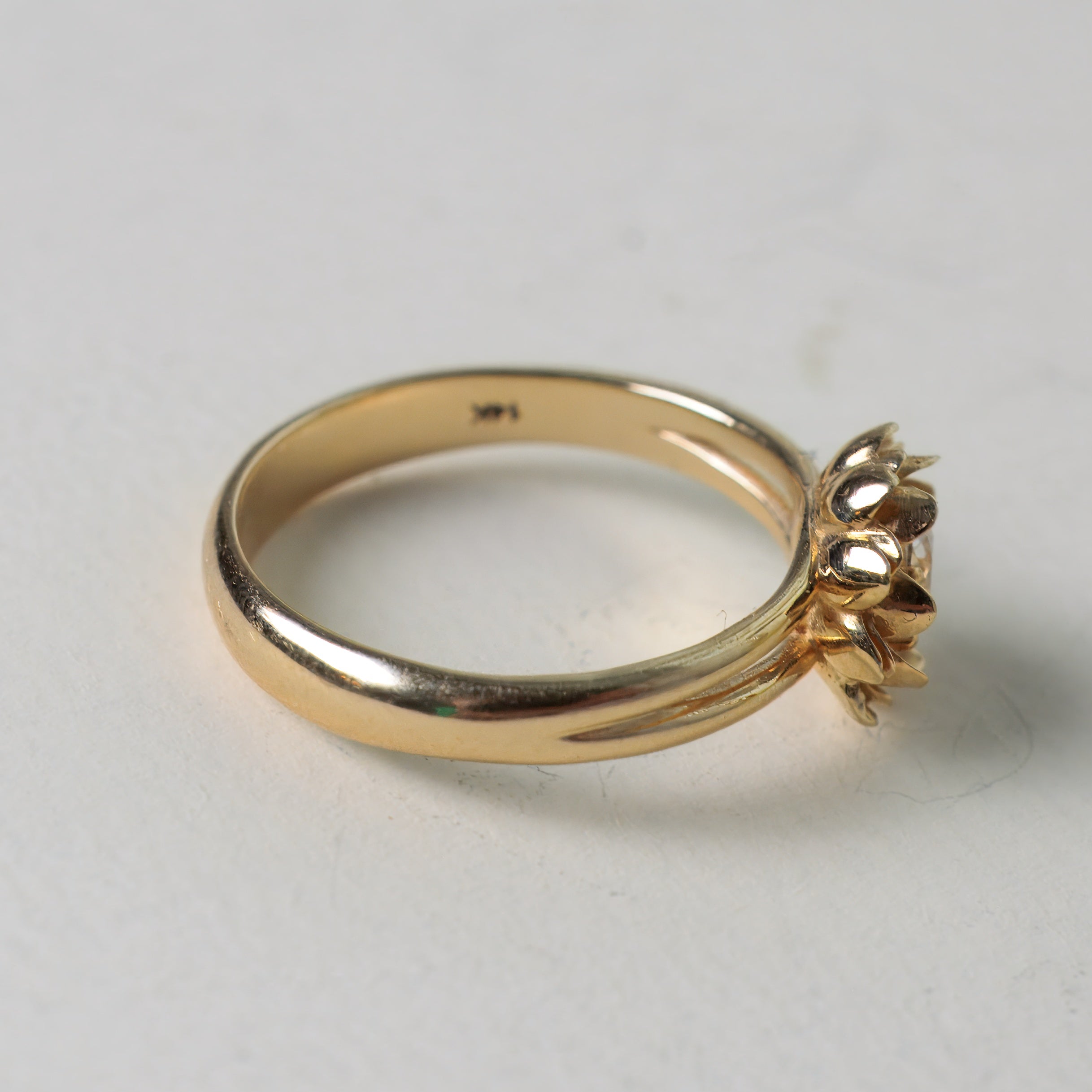 Gold ring with a diamond on a light gray background