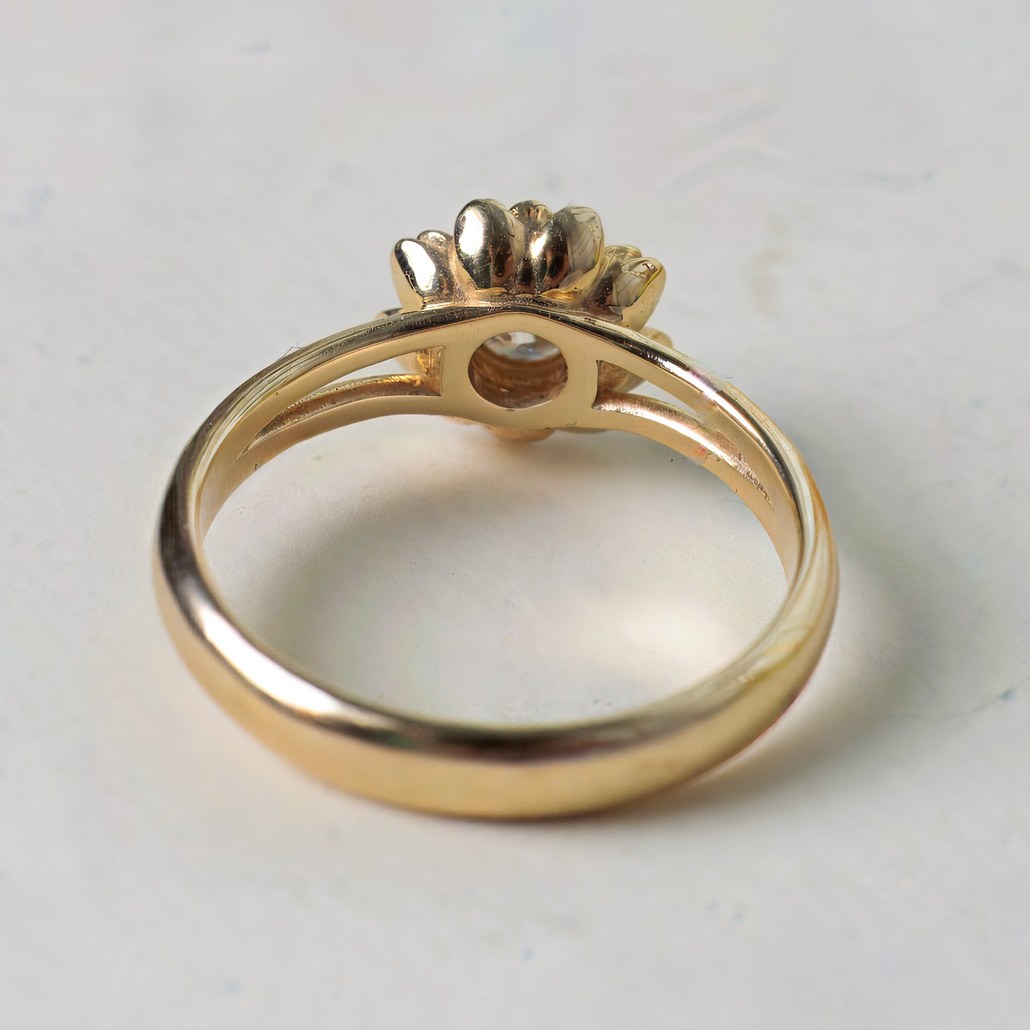 Gold ring with a decorative top on a light gray background