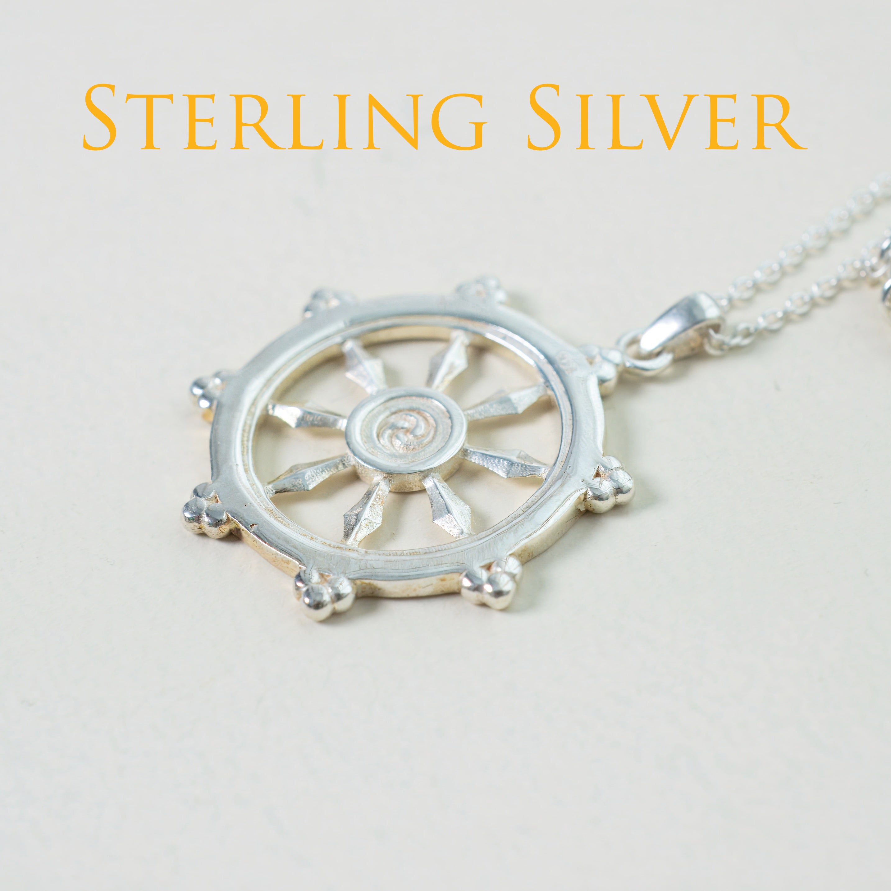 Silver wheel pendant necklace on a light background with 'STERLING SILVER' text.