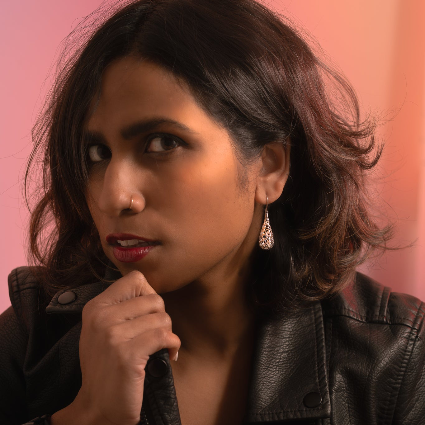 Woman wearing a black leather jacket against a pink background