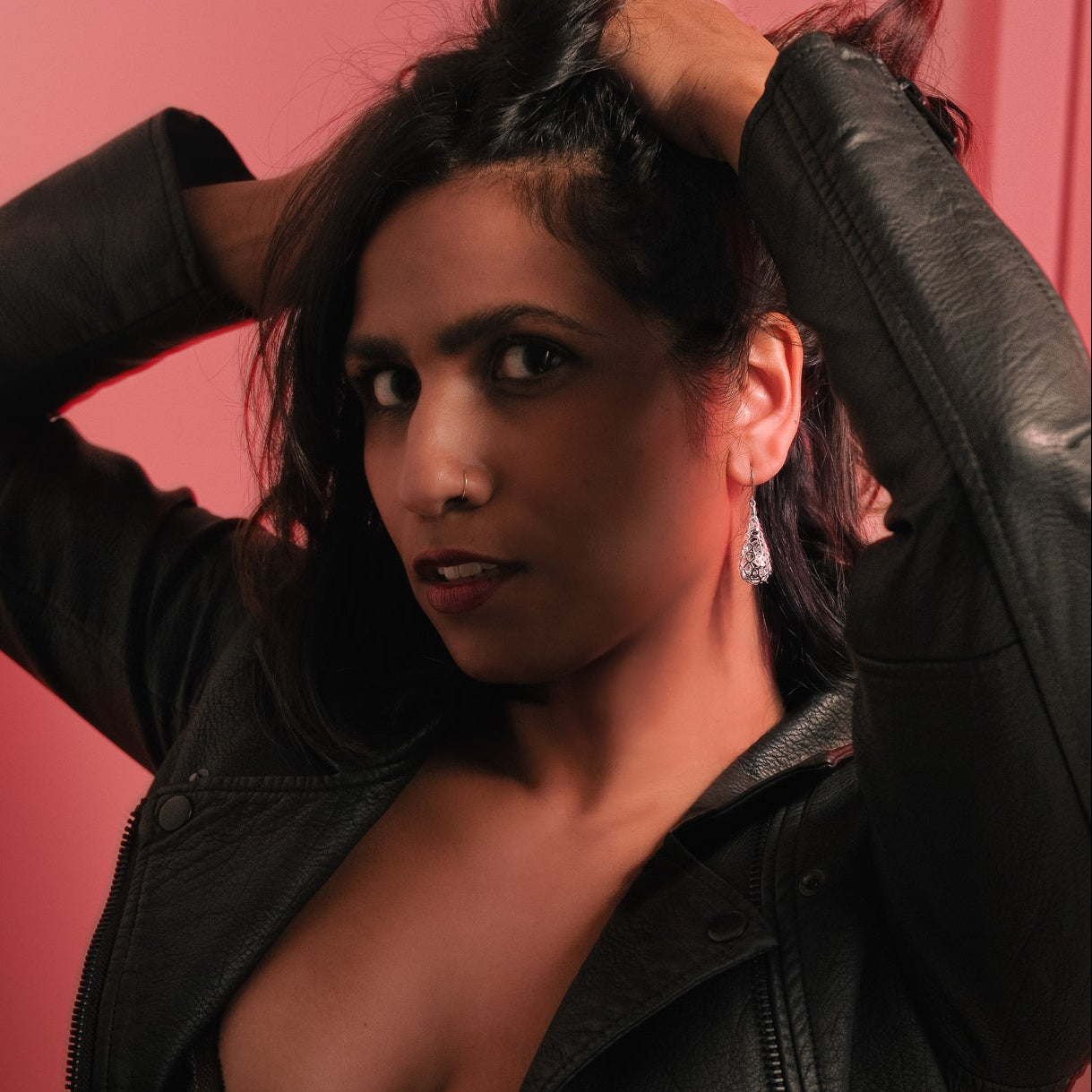 Woman wearing a black leather jacket against a red background