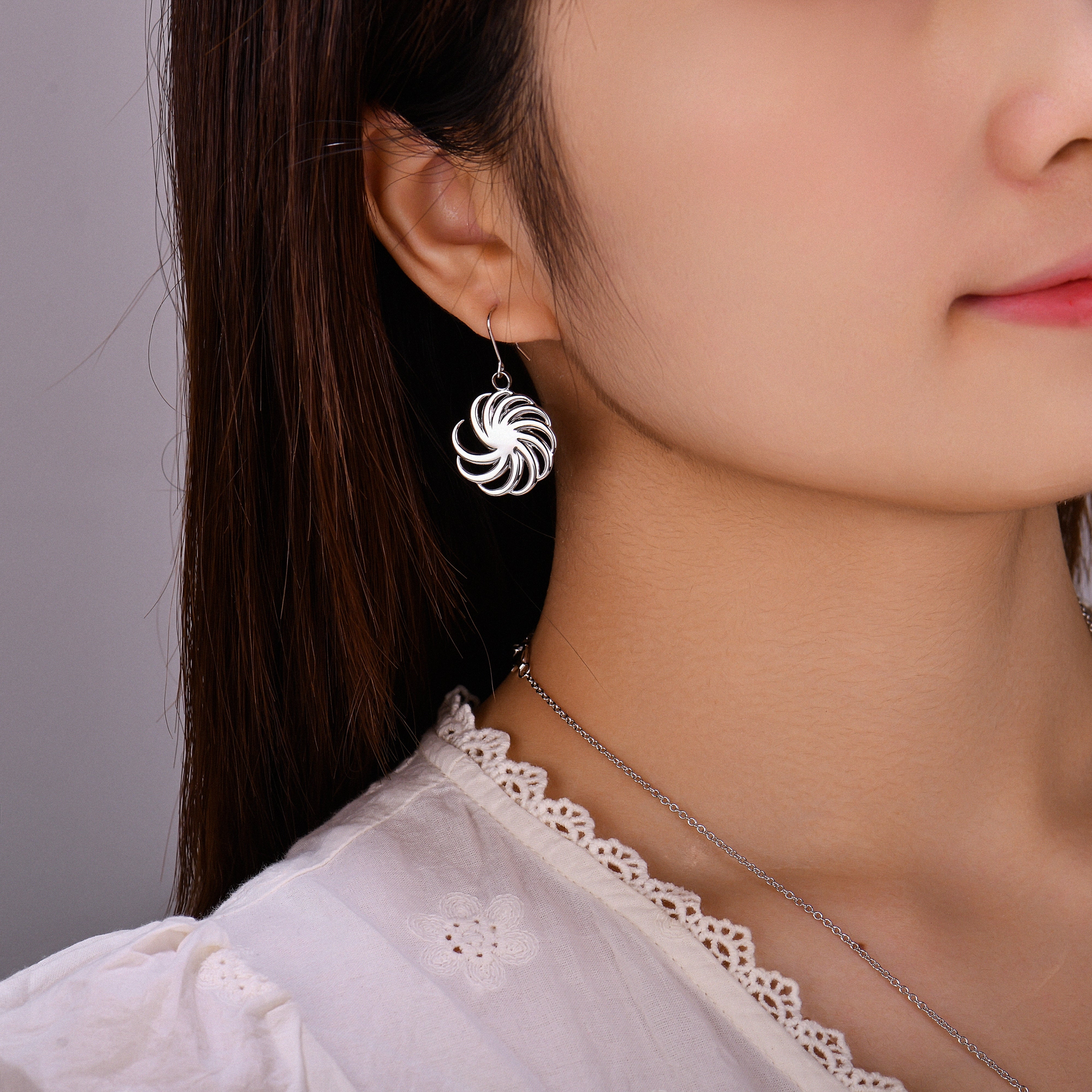 Close-up of a person wearing a silver earring with a swirling design.