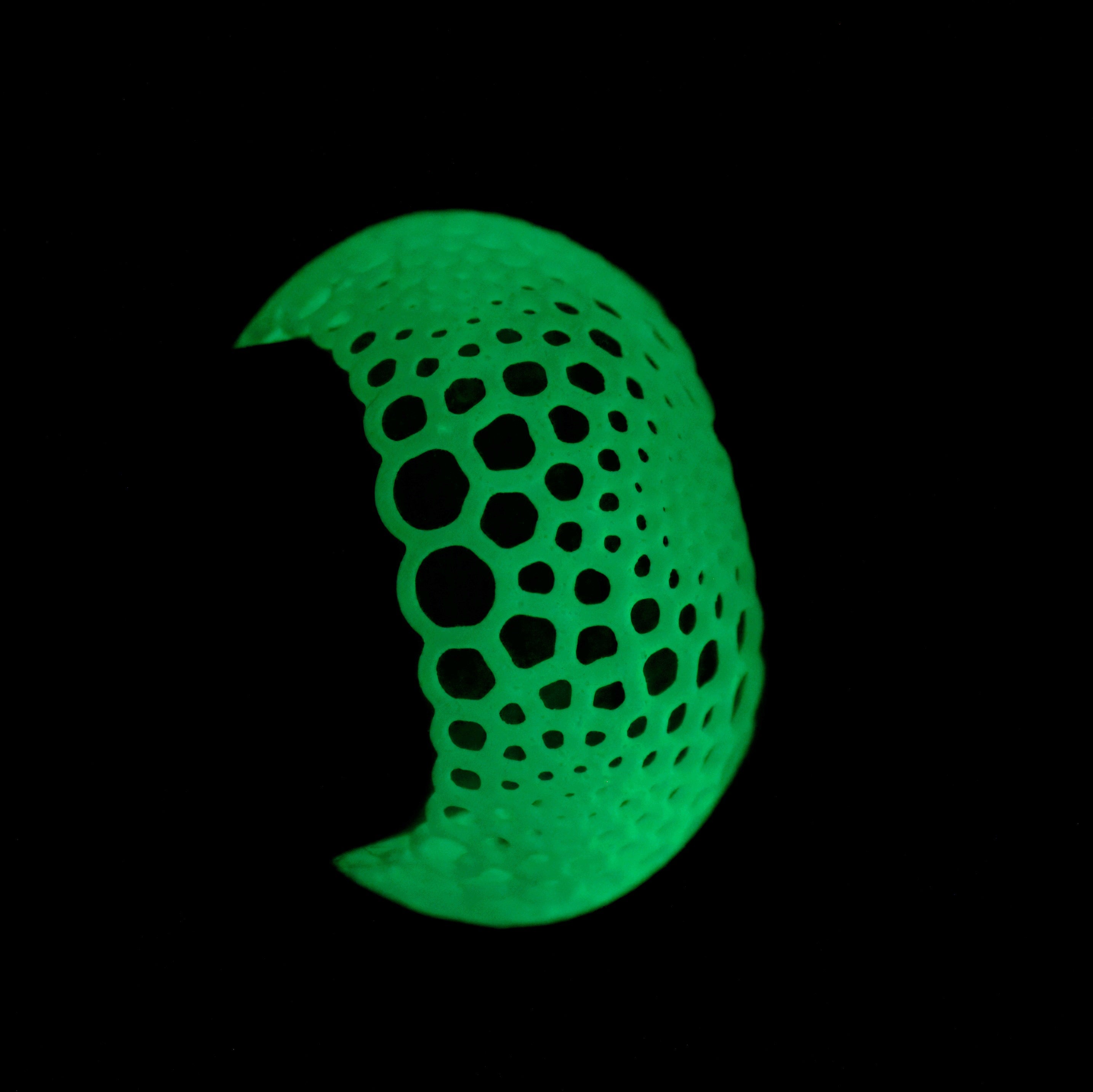 Glowing green bangle bracelet on a wrist on a black background in the dark