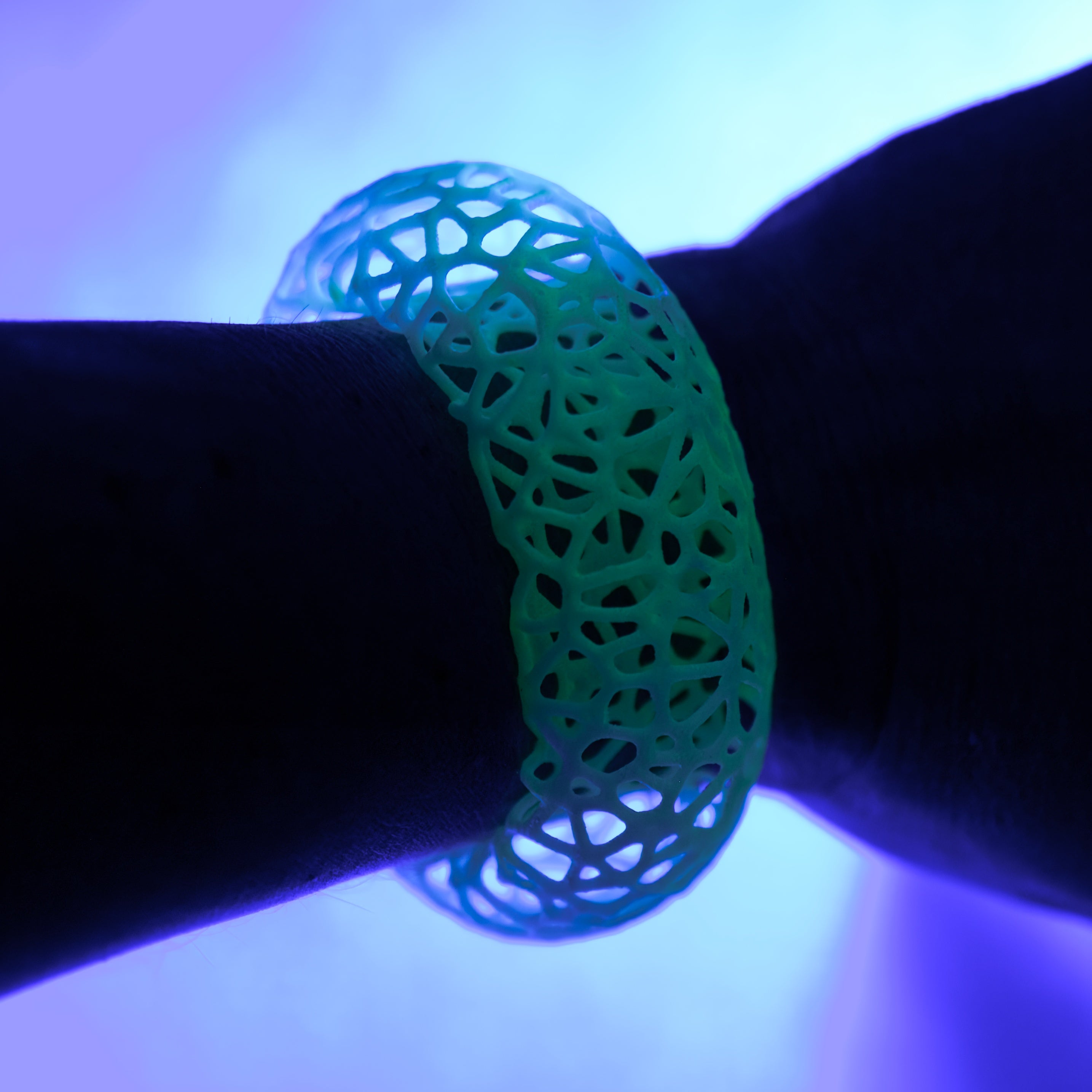Glowing green bracelet on a wrist under purple black light