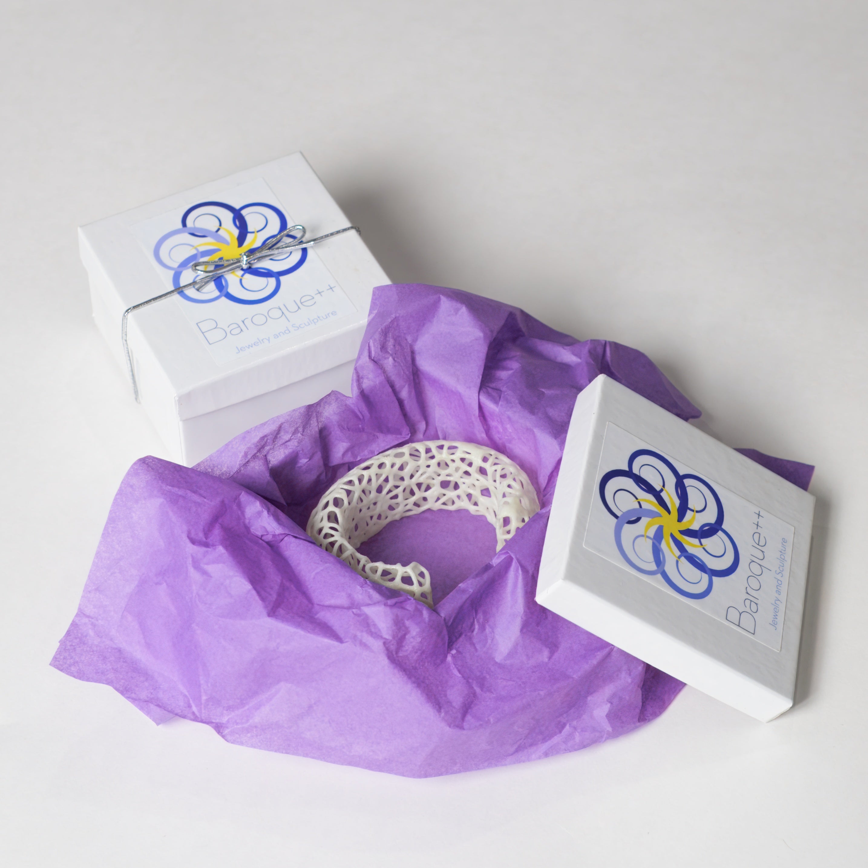 Silver bracelet on purple tissue paper with Baroque+ packaging in the background