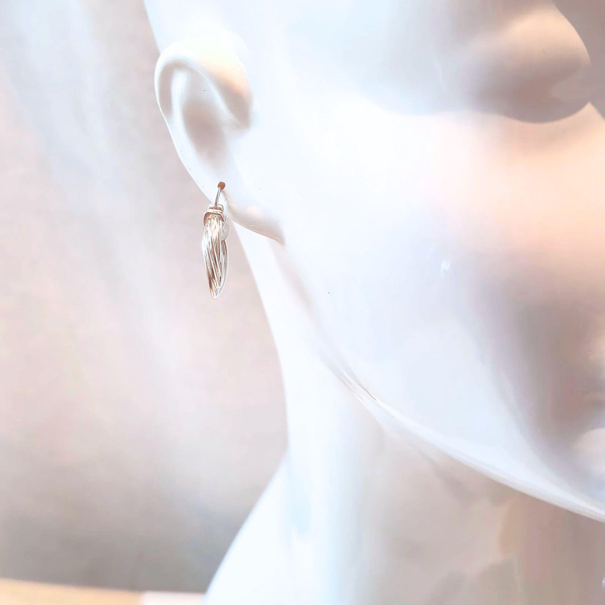Silver Orbit hoop earrings on a white mannequin