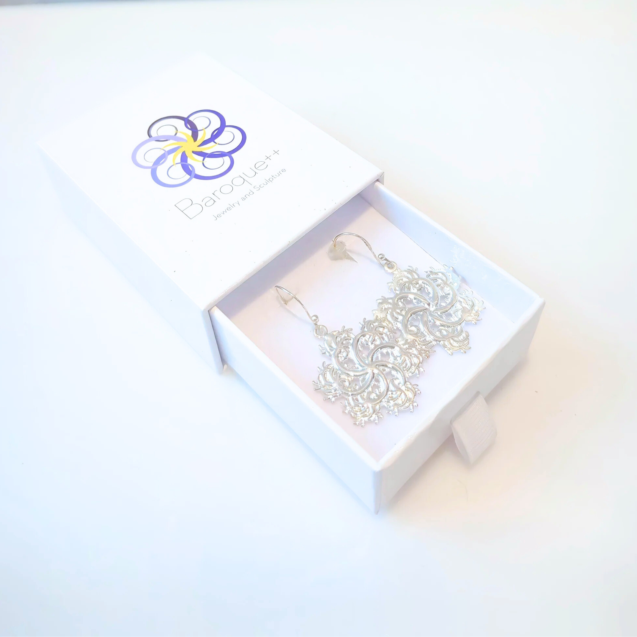 Six-pointed fractal earrings pair in box with logo on white surface