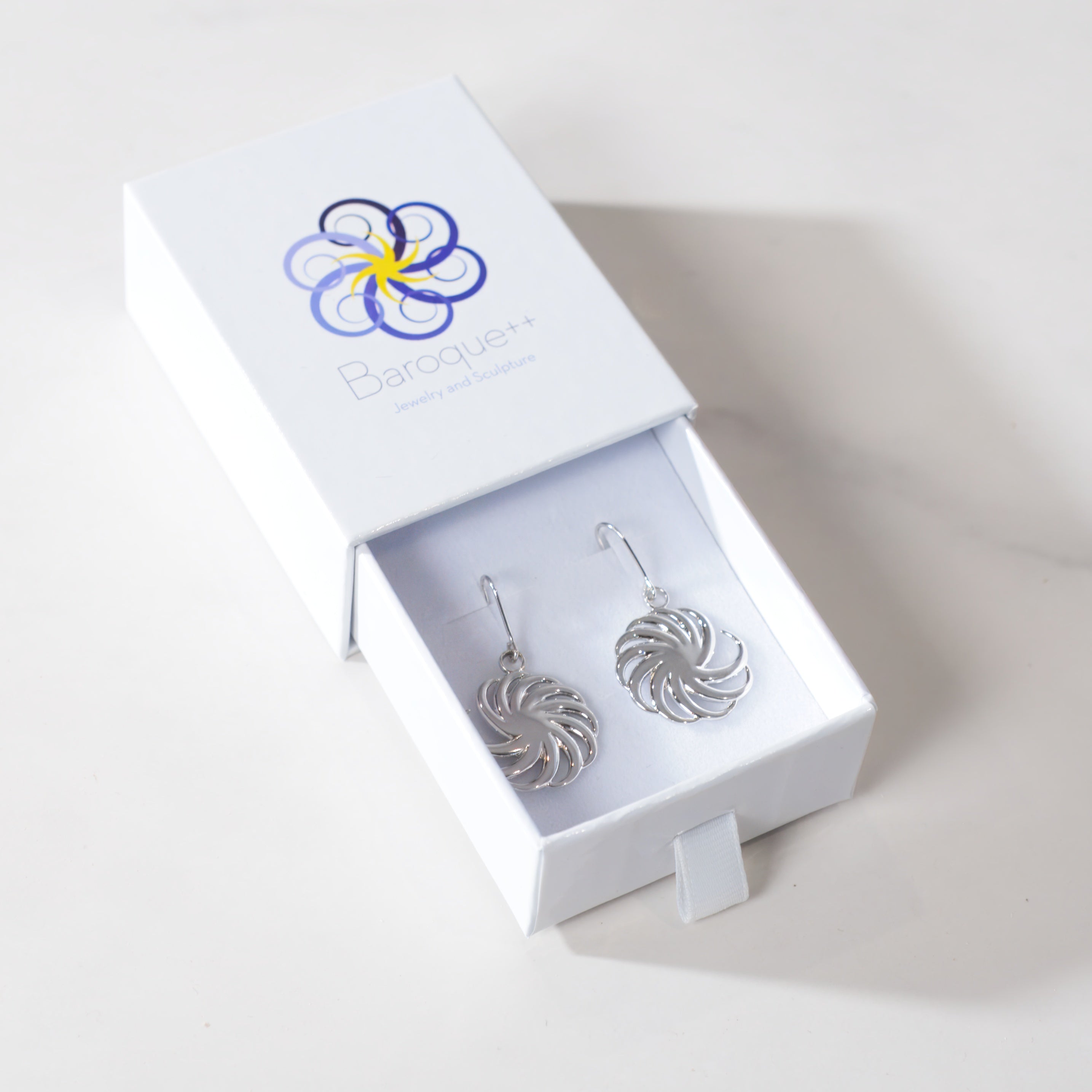 Silver earrings in a white box with a brand logo on a light background
