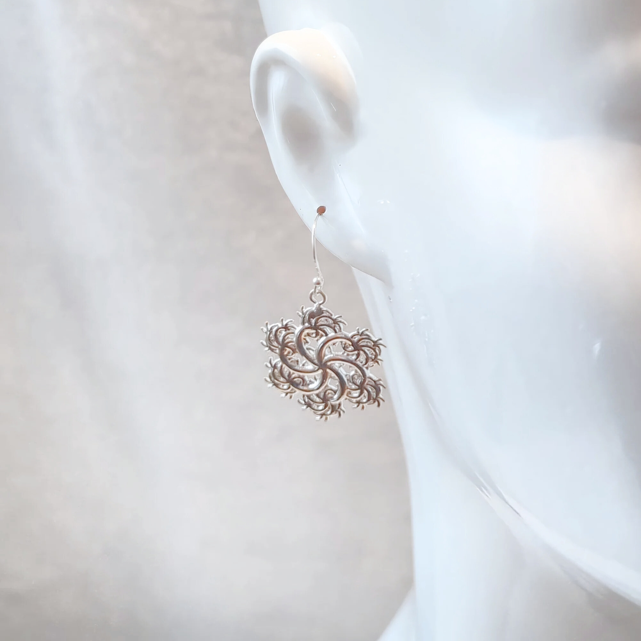 a close up of the six-pointed-earrings in silver on white mannequin on in front of white backgrop