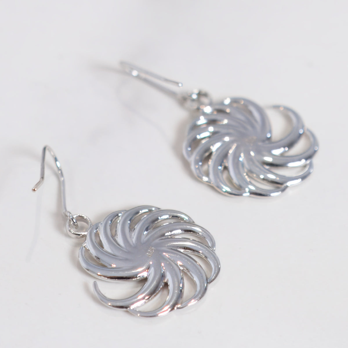 Spiral Earrings in sterling silver on a light gray background