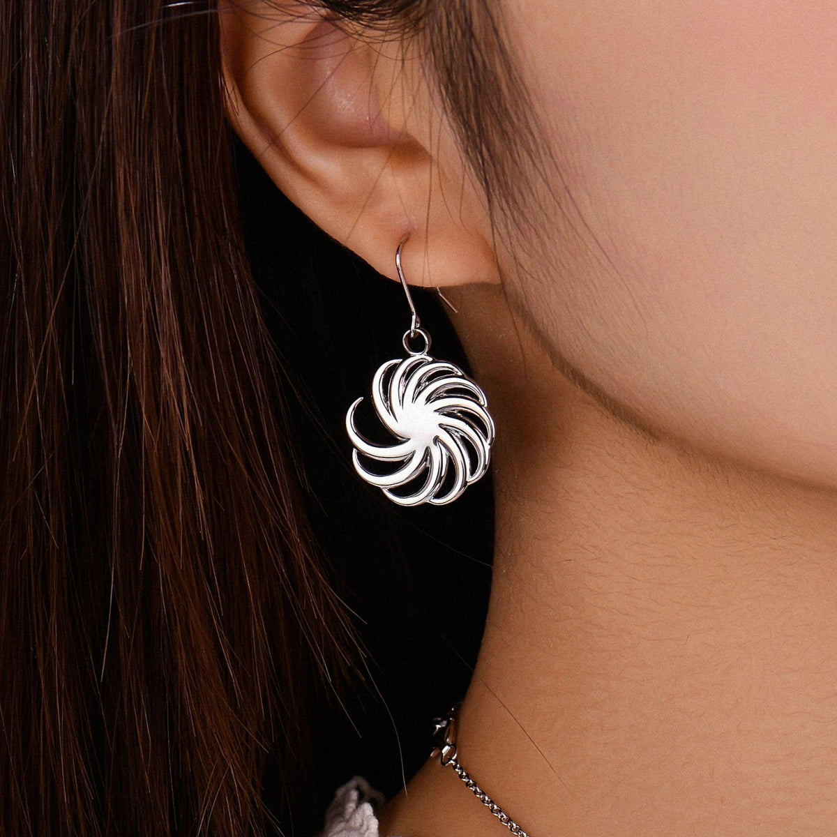 Spiral earring worn on the ear, showing the neckline