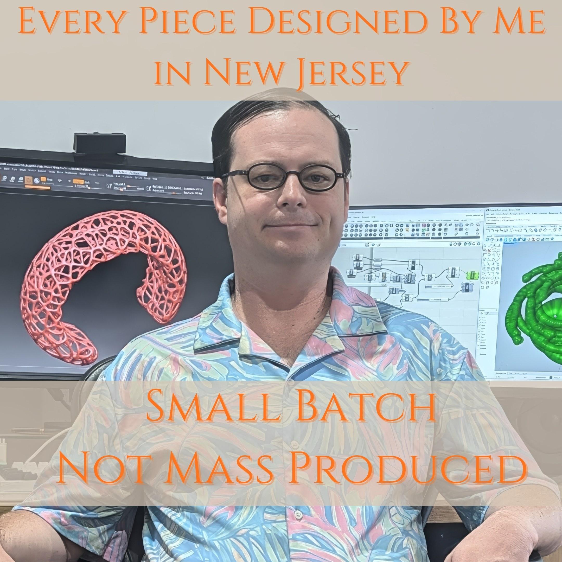 a man sitting in ffacing away from a desk with two computer screens on a desk with the text "Every piece designed by me in New Jersey, small batch not mass produced."