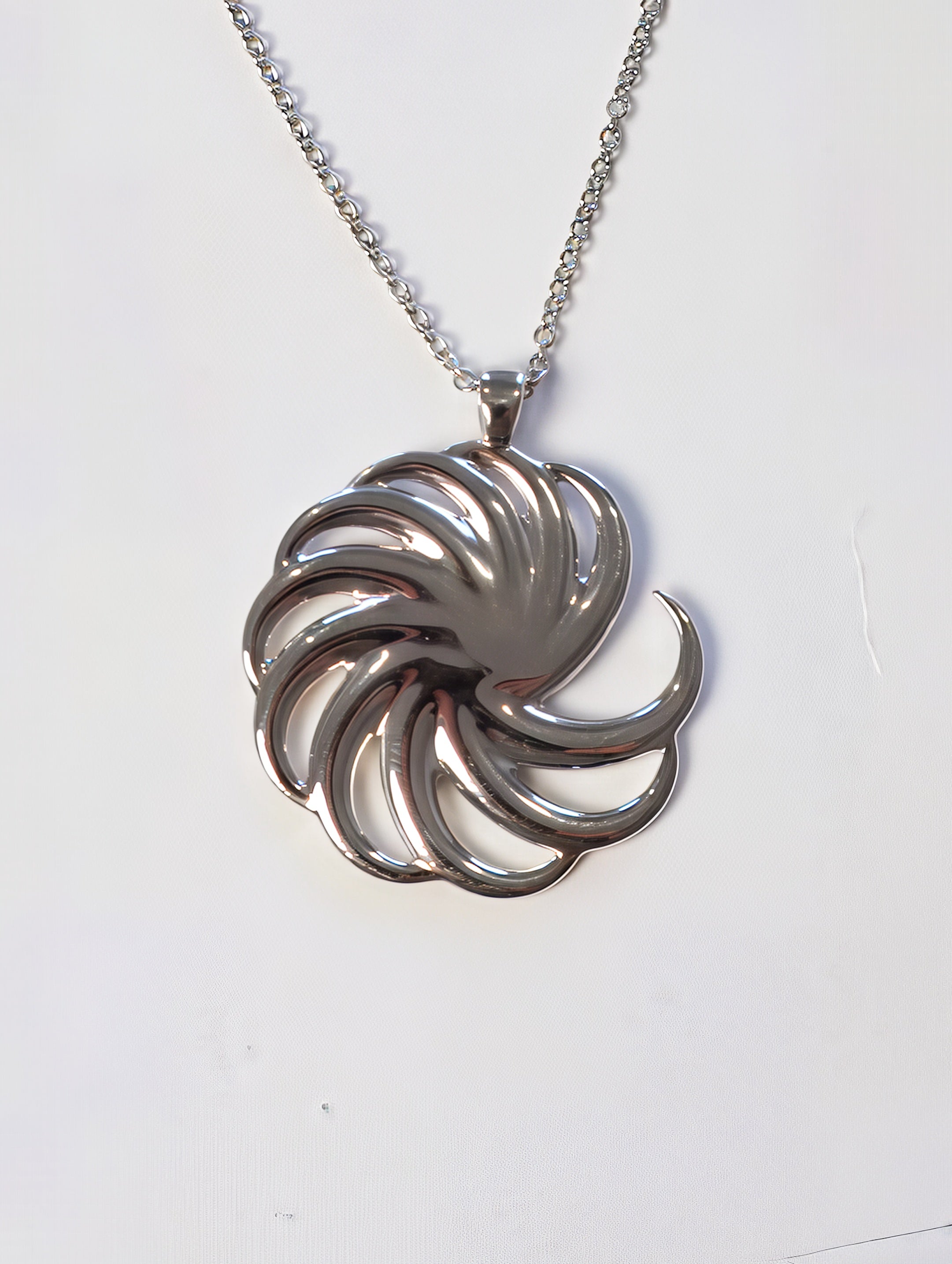 A round sterling-silver spiral pendant on a silver chain
