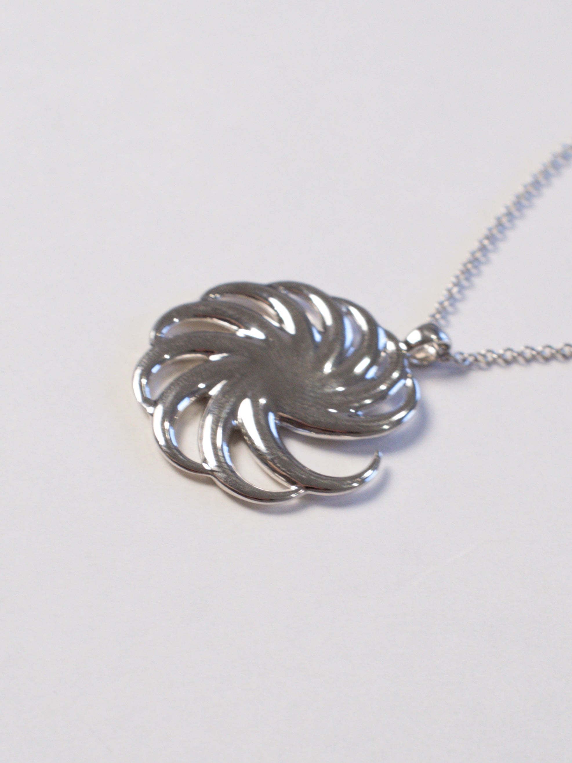 close up of silver spiral pendant at an obliquen angle