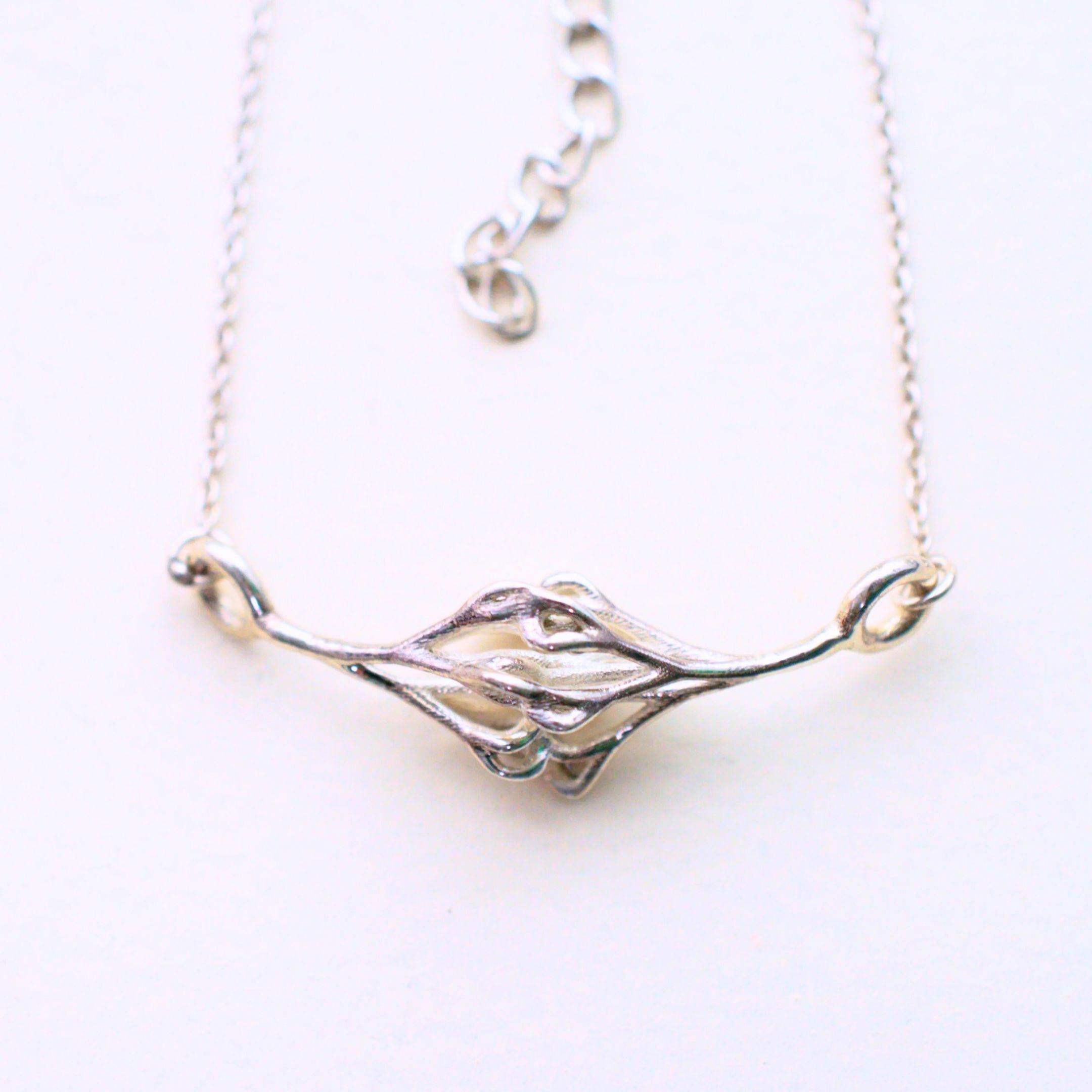 a capillary-shaped sterling silver pendant on  a chain with a white background