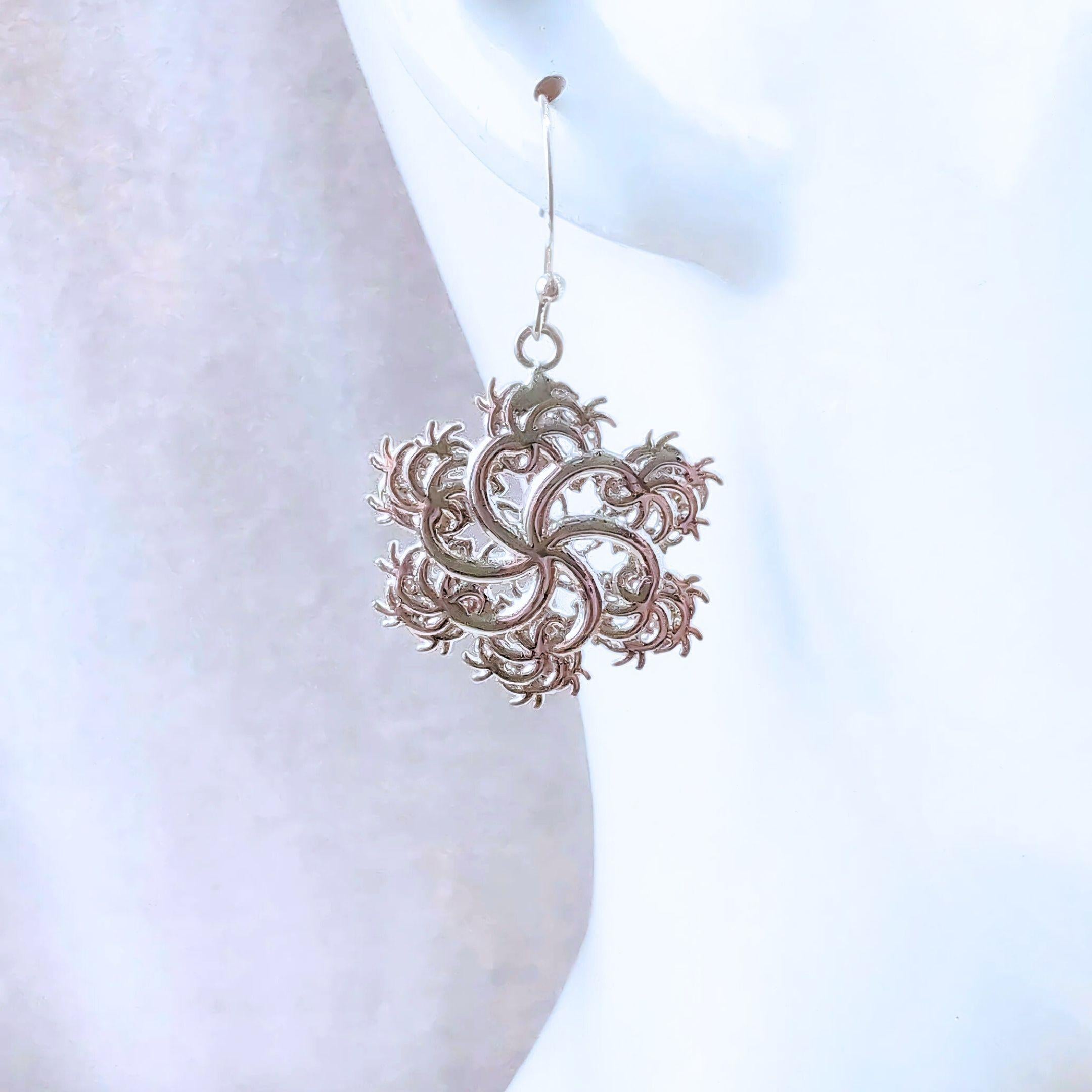 Close up of six-pointed fractal earring on white mannequin on white background