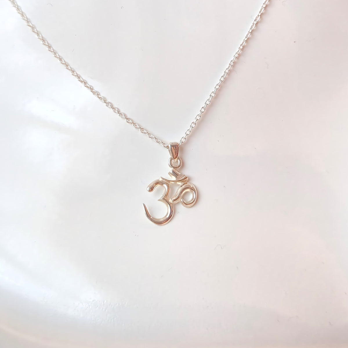 Silver om symbol pendant necklace on a white background