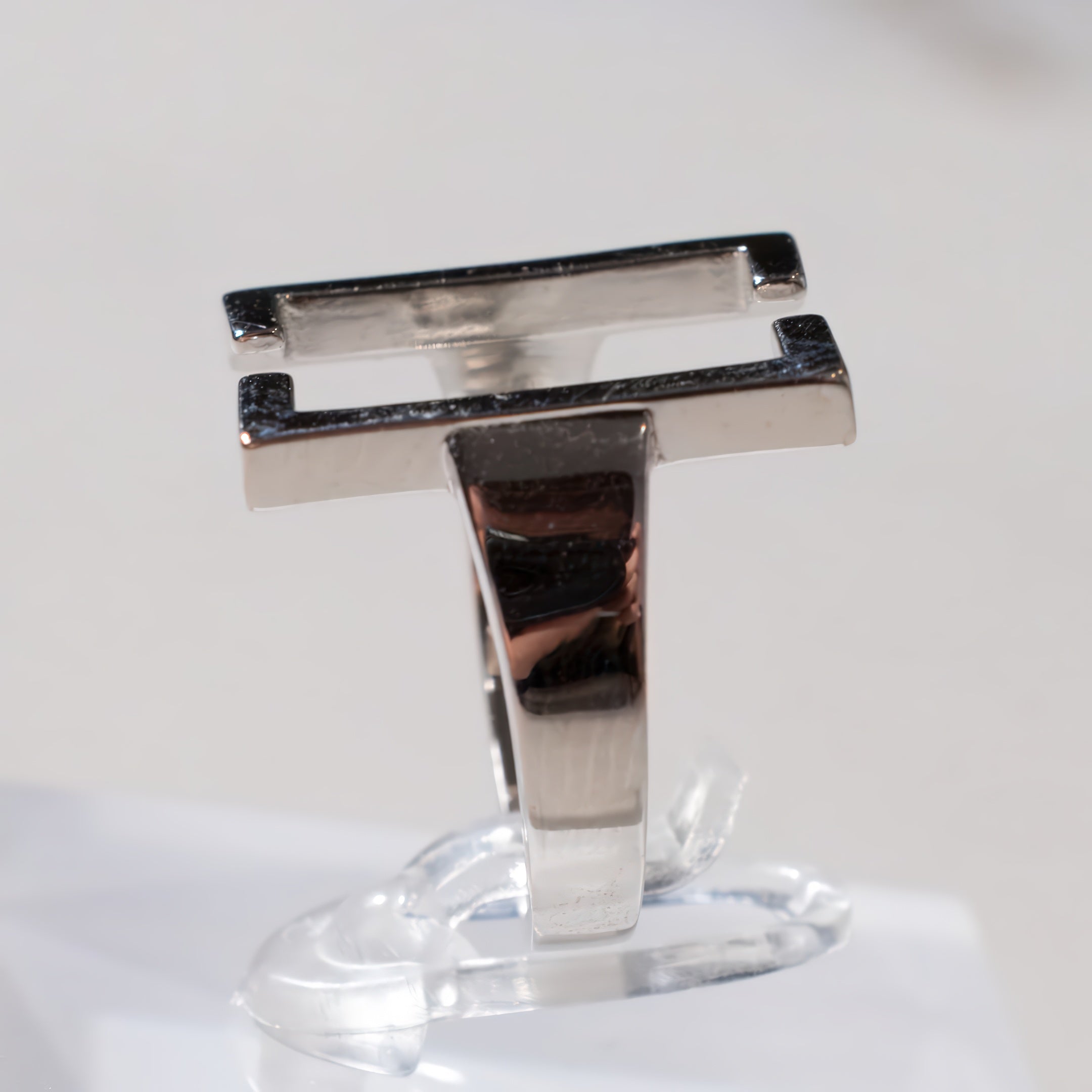 Silver ring on a clear stand against a white background