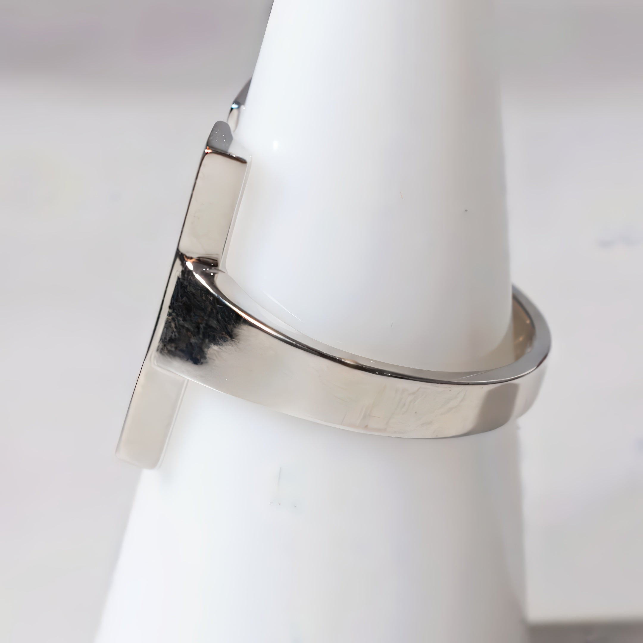 Silver ring on a white cylindrical object with a plain background