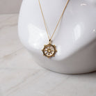 Gold  necklace with a decorative dharma wheel pendant on a white mannequin bust.