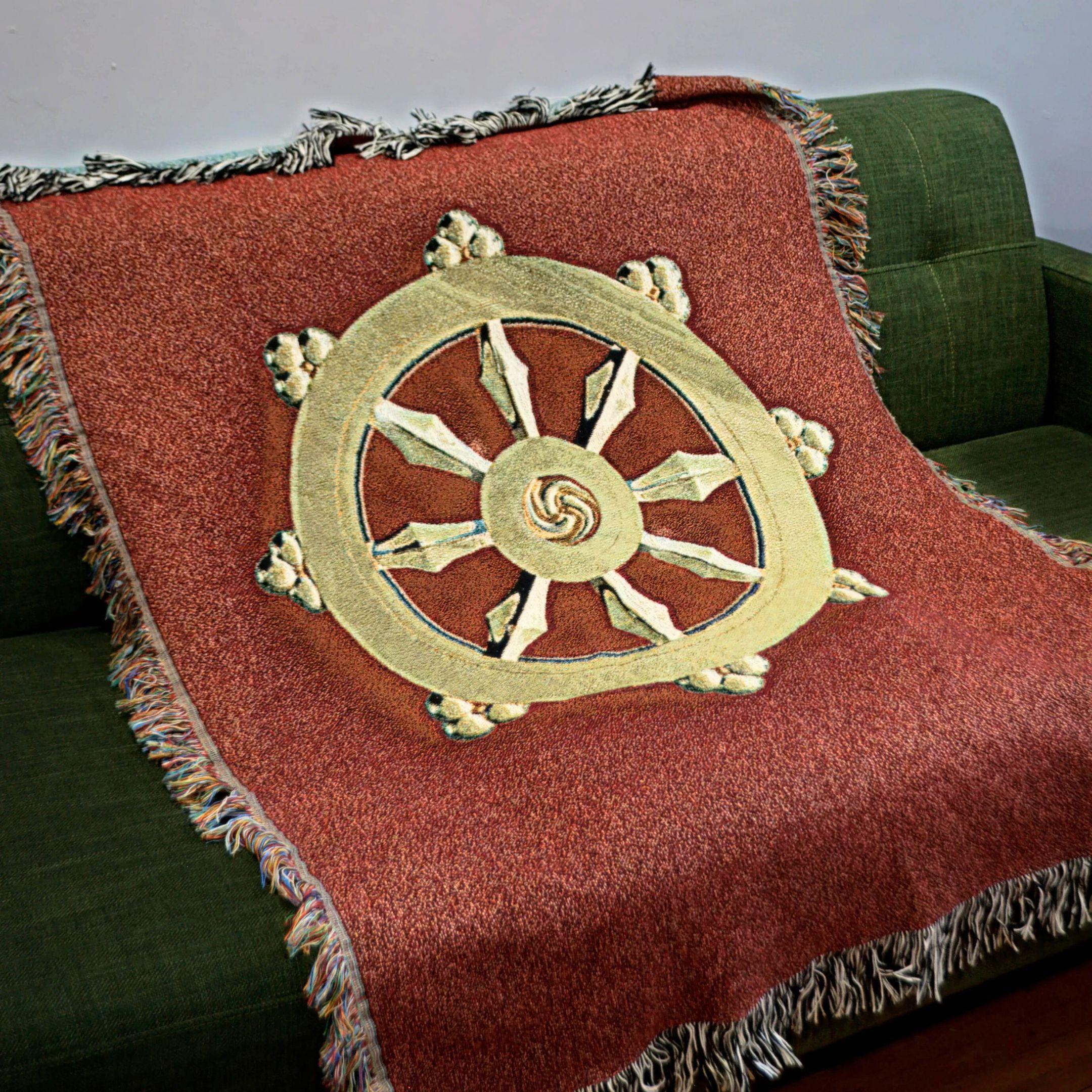 a red blanket with gold dharma wheel on green couch