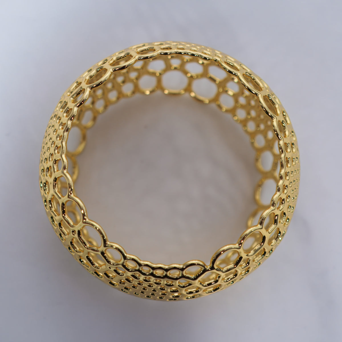 Gold Foam Bangle, an openwork statement bracelet on light gray