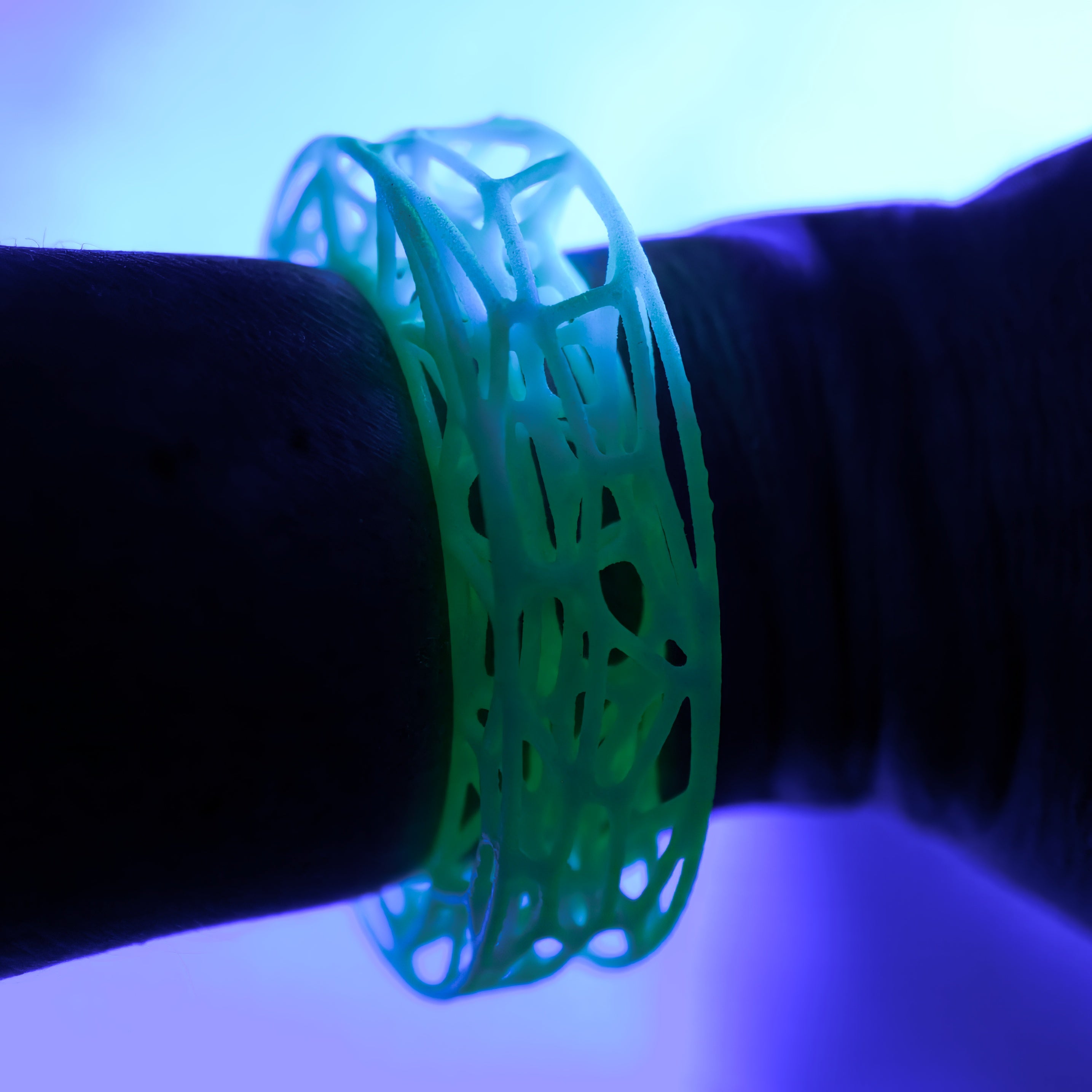 Green bracelet with a unique pattern on a wrist under a blue light