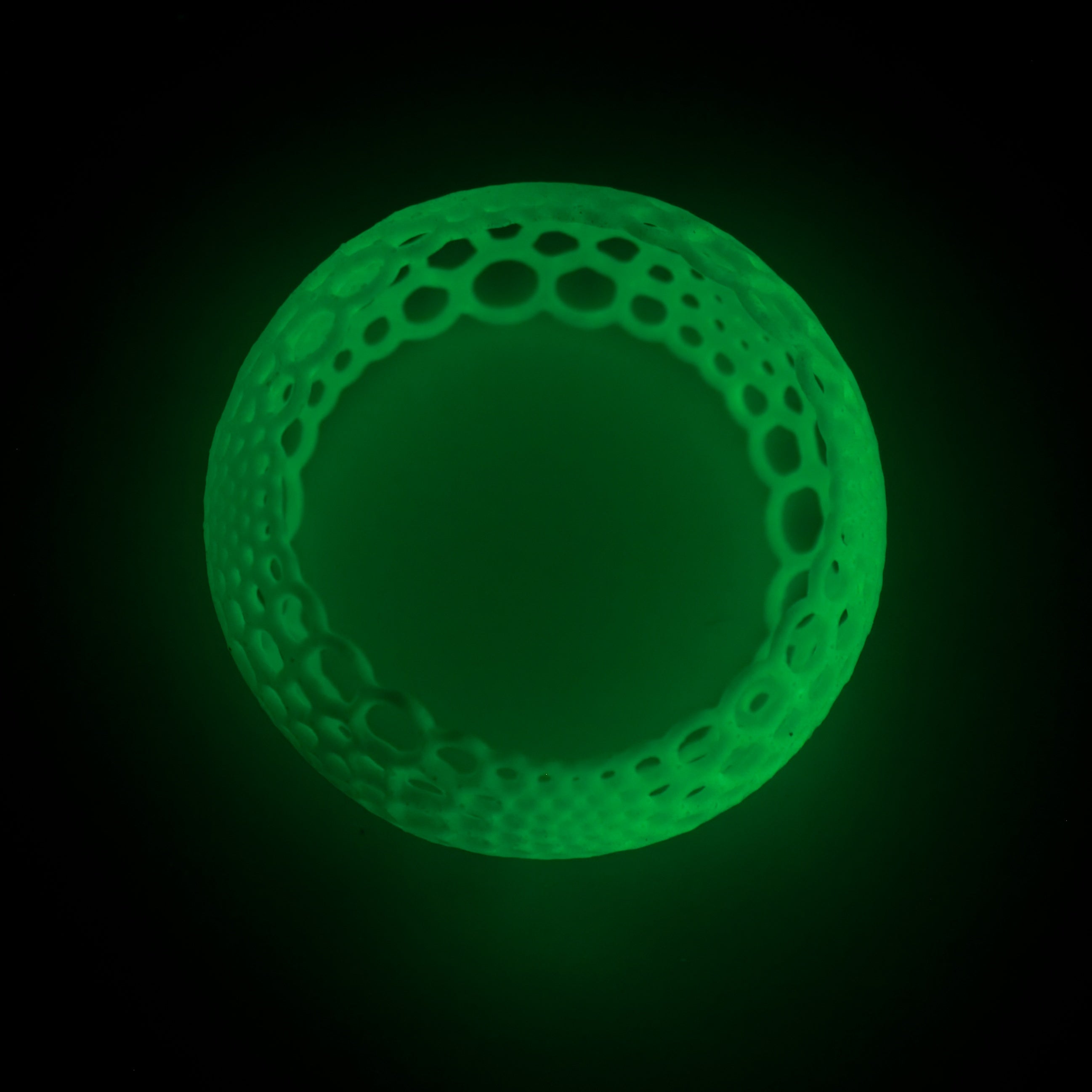 a glowing green ring bangle bracelet on a black background in the dark