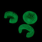 Three green, textured, intricately designed bracelets on a black background