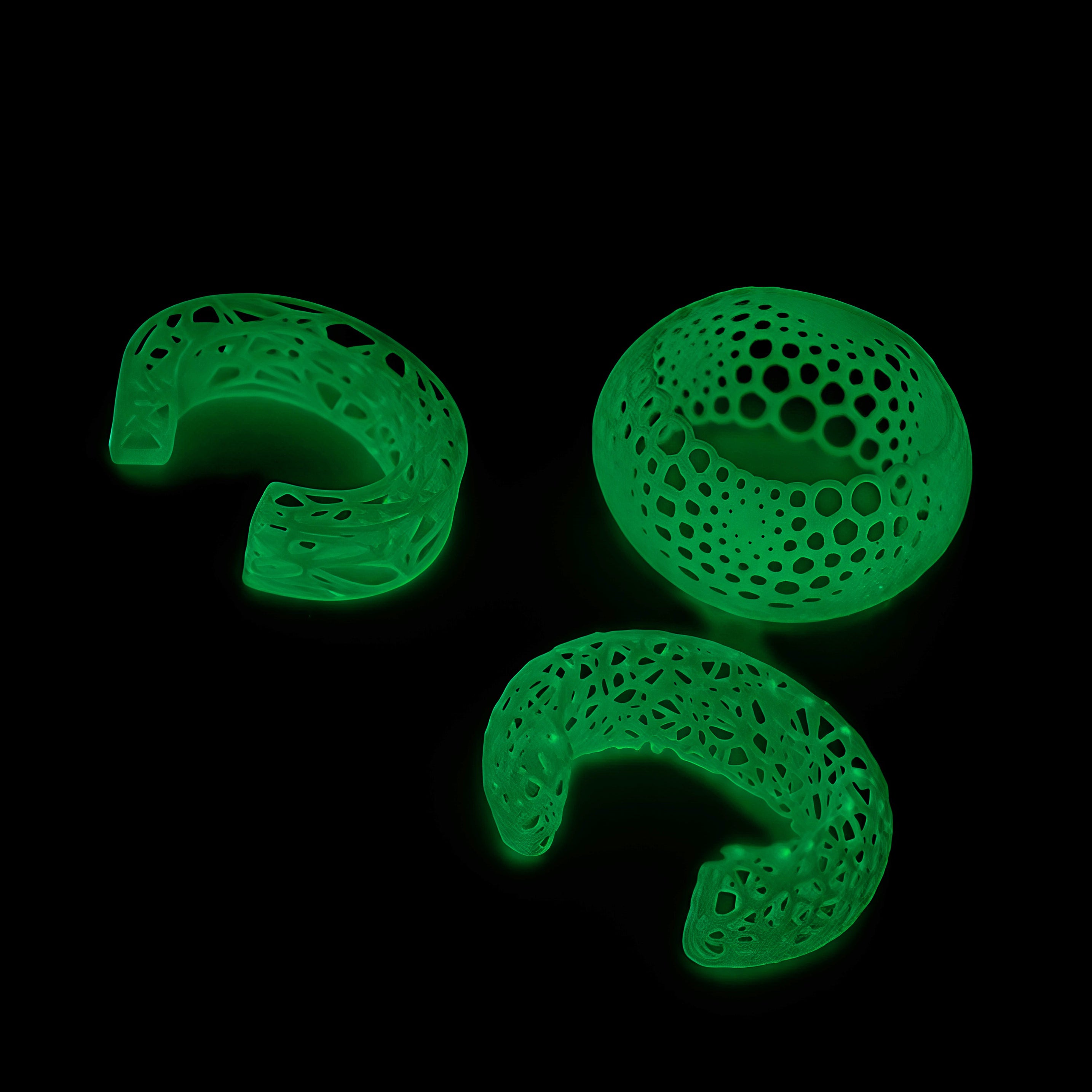 Three green, textured, intricately designed bracelets on a black background
