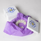 Decorative item with purple tissue paper and branded box on a white background
