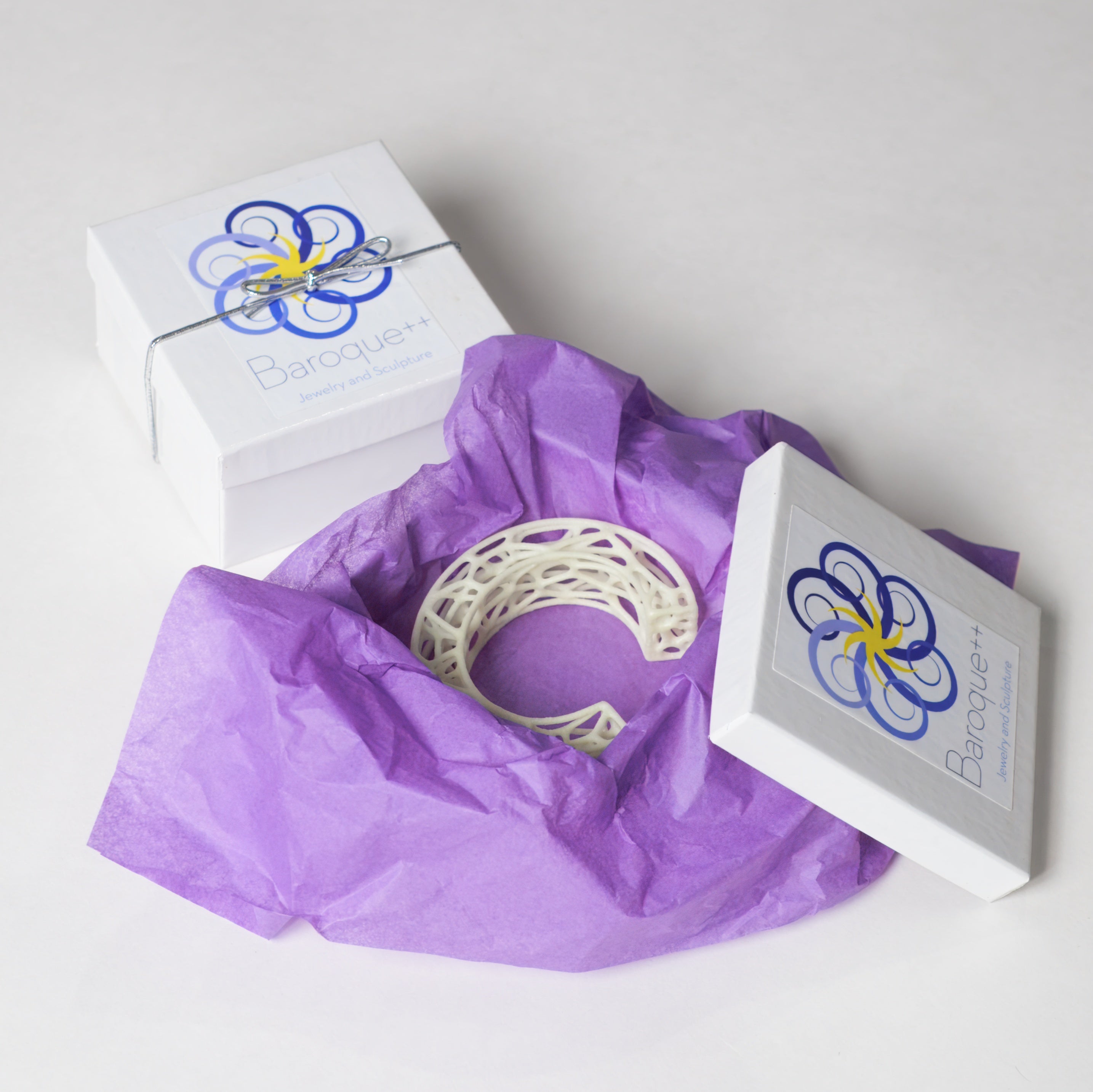 Decorative item with purple tissue paper and branded box on a white background