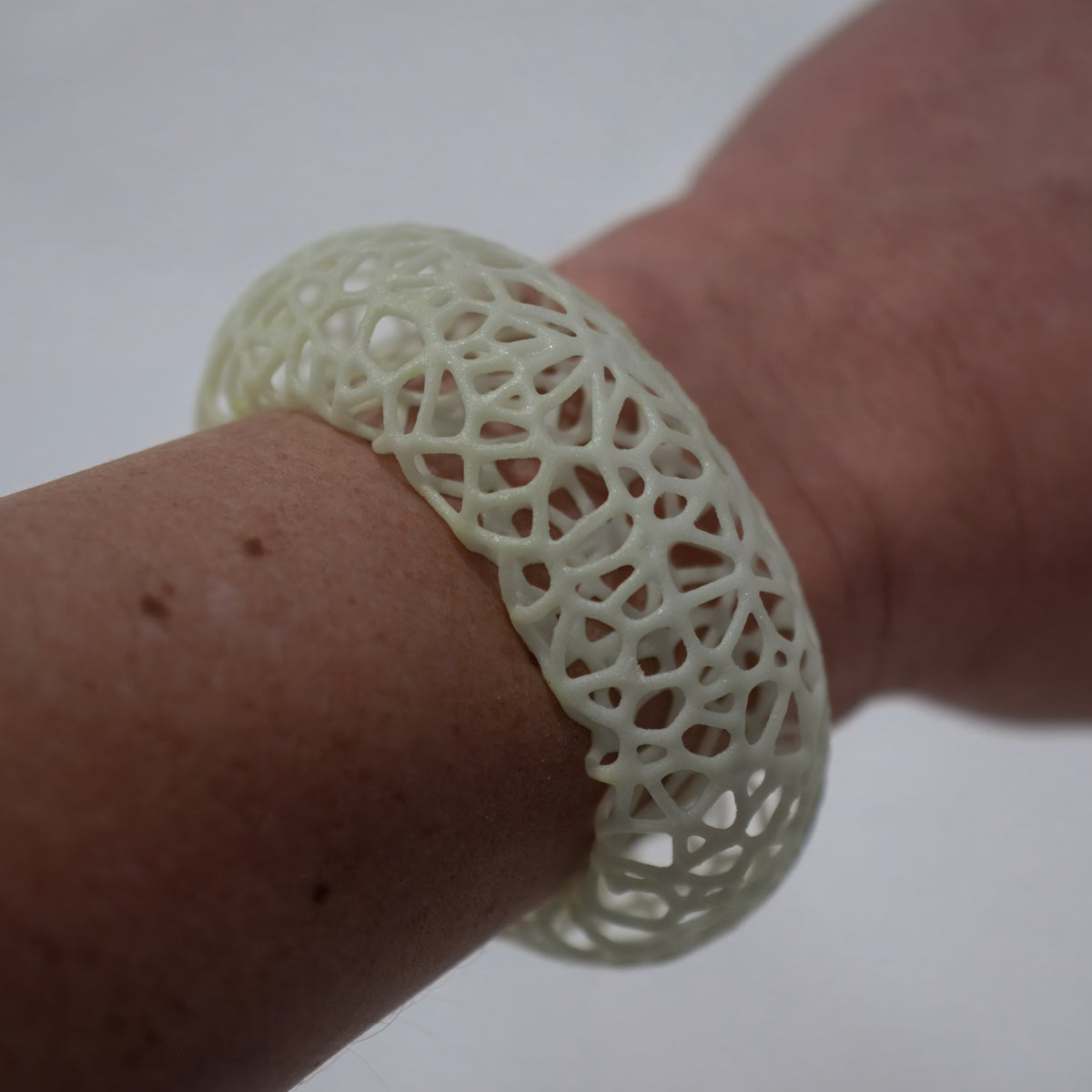 Glow Symbiote Cuff in daylight, a white cuff on a wrist