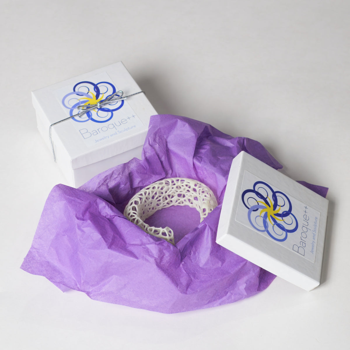 Glow Symbiote Cuff packaged in purple tissue paper with a Baroque++ box