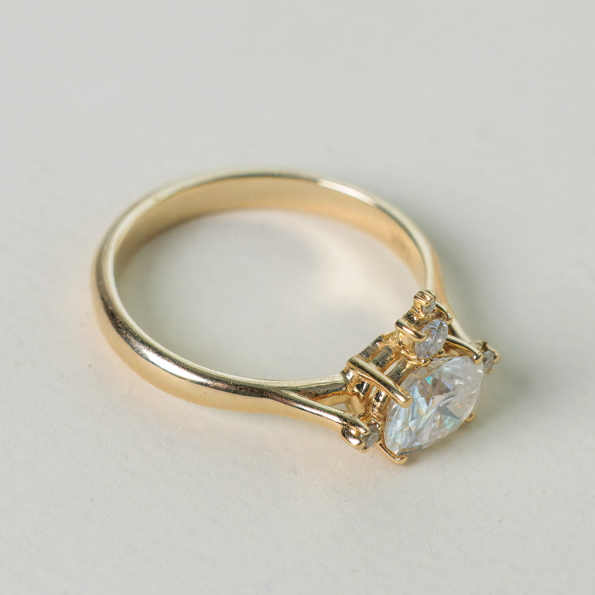 Mandelbrot oval diamond engagement ring in gold on a light gray background