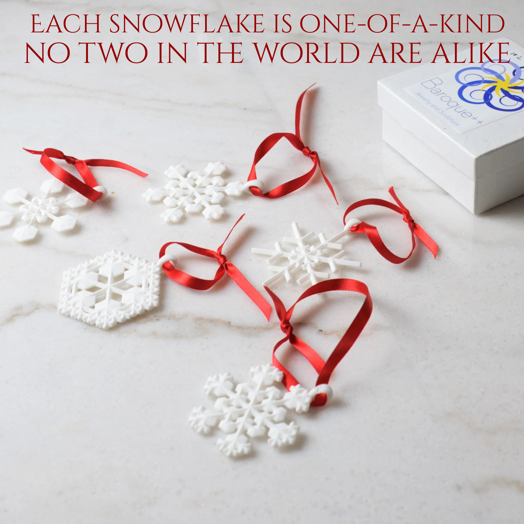 Five white snowflakes with red ribbons on a white marble table. with a white box with logo. Text at top says "each-snowflake is one-of-a-kind no two in the world are alike."