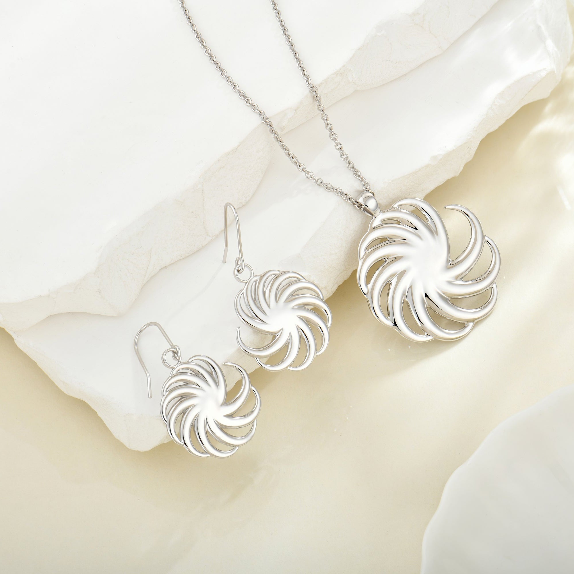 Silver round spiral necklace and earrings jewlry set including earrings and a necklace on a white fabric background