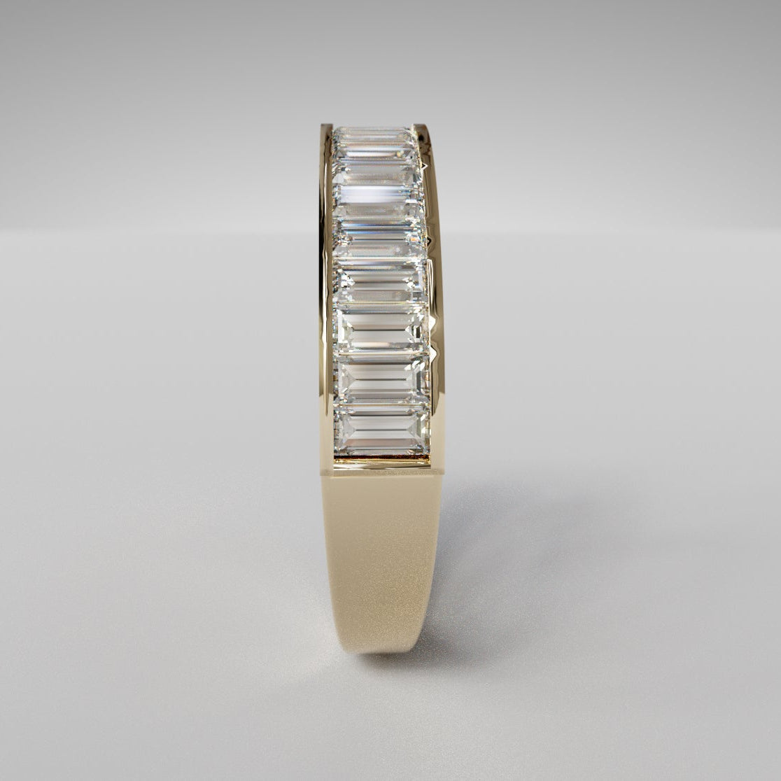 Gold ring with emerald-cut diamonds on a gray background