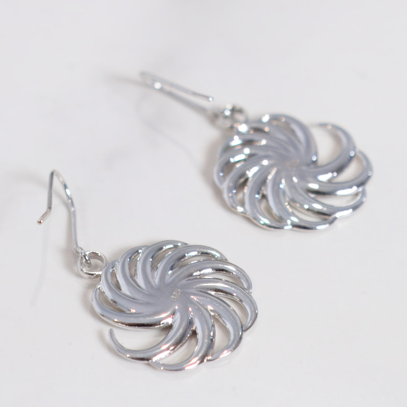 Silver spiral earrings on a light gray background