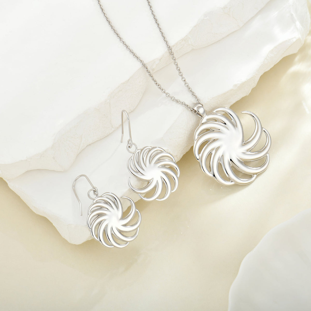 Silver Spiral necklace and earrings set on white fabric