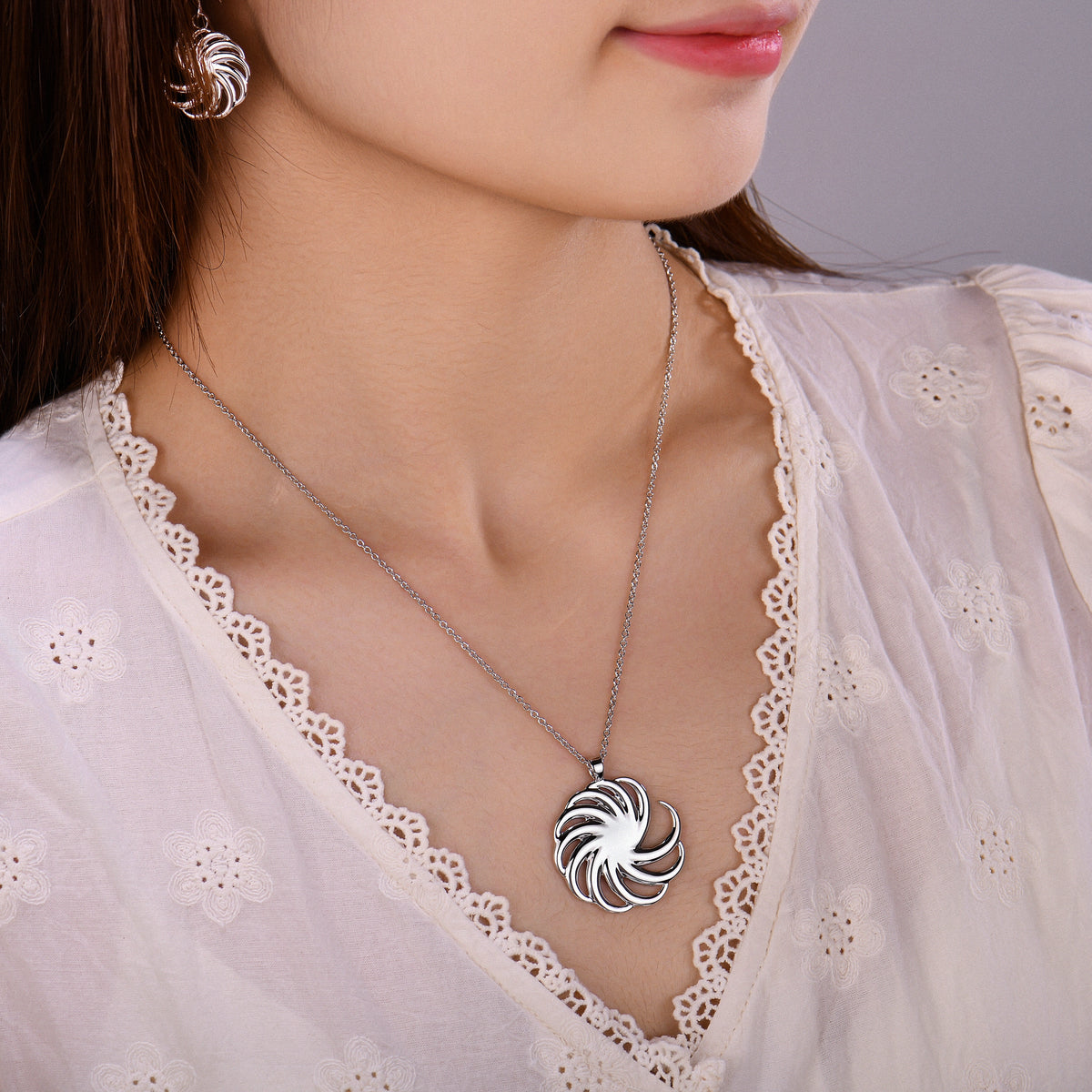 Woman wearing the Spiral Pendant with matching Spiral earrings