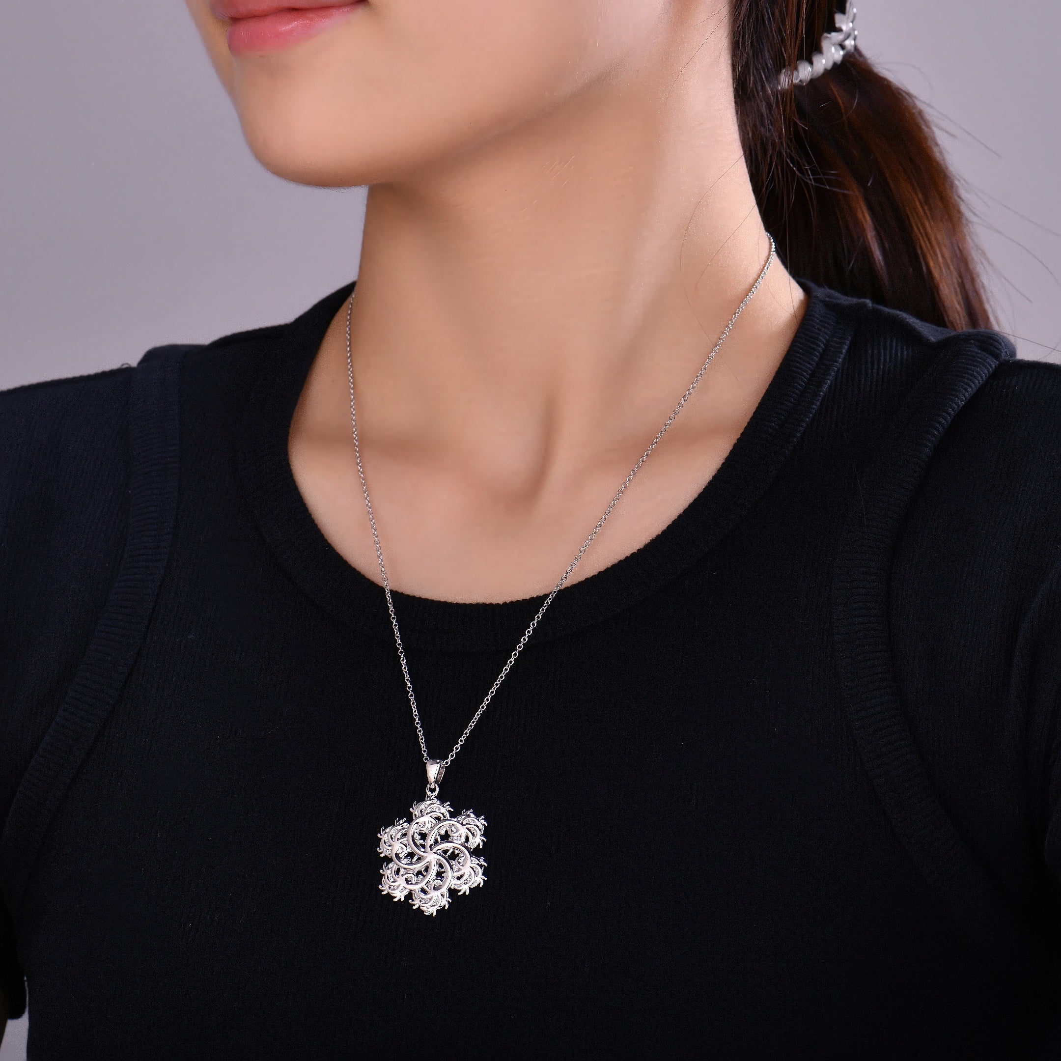 Silver six-pointed pendant with a snowflake pendant worn by a person against a neutral background
