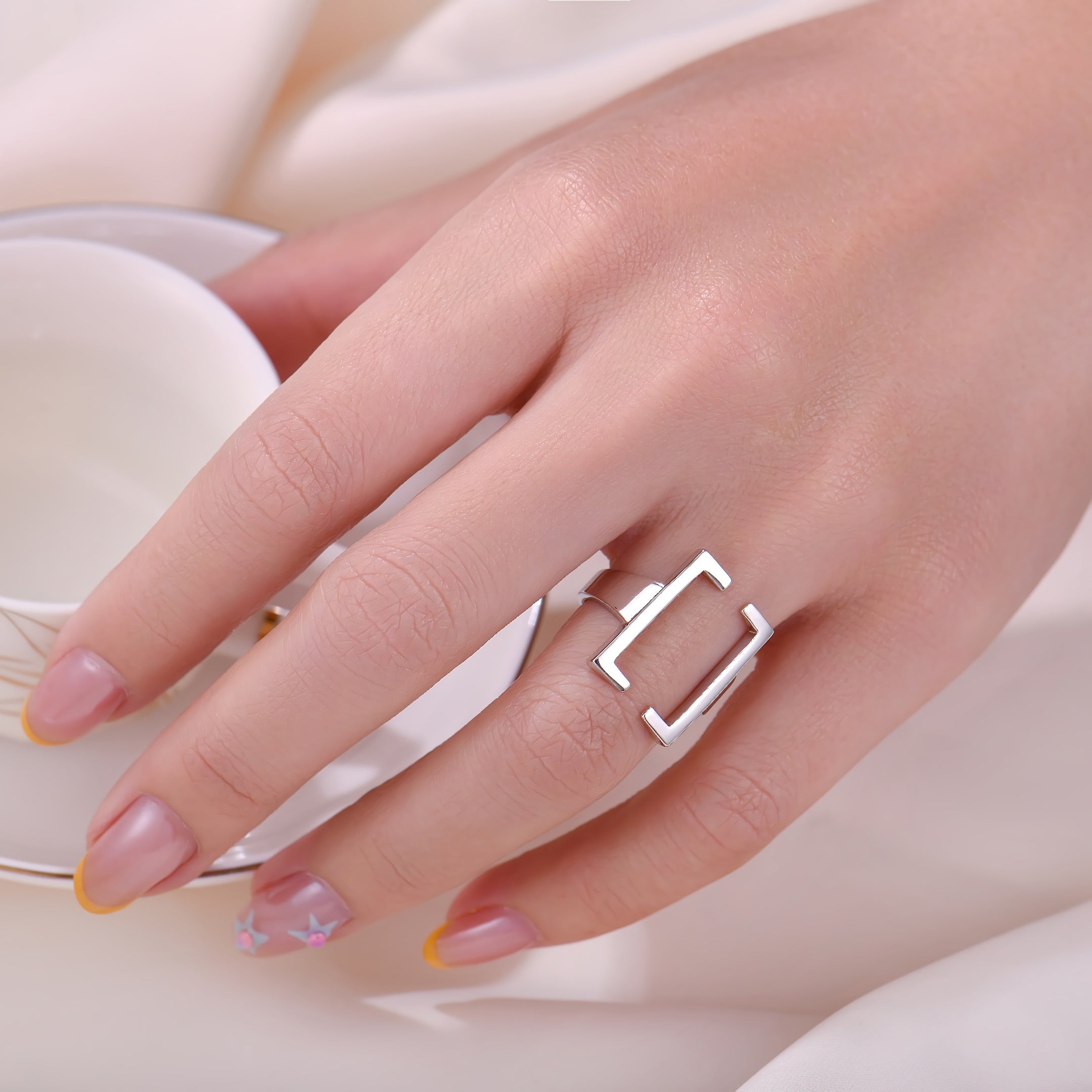 Hand wearing a silver ring with a white background